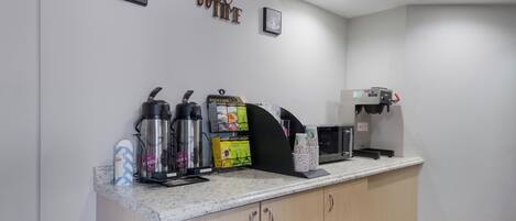 Eine Kaffeestation mit Kaffeemaschine, Wasserkochern und einer Kaffeetassenhalterung.