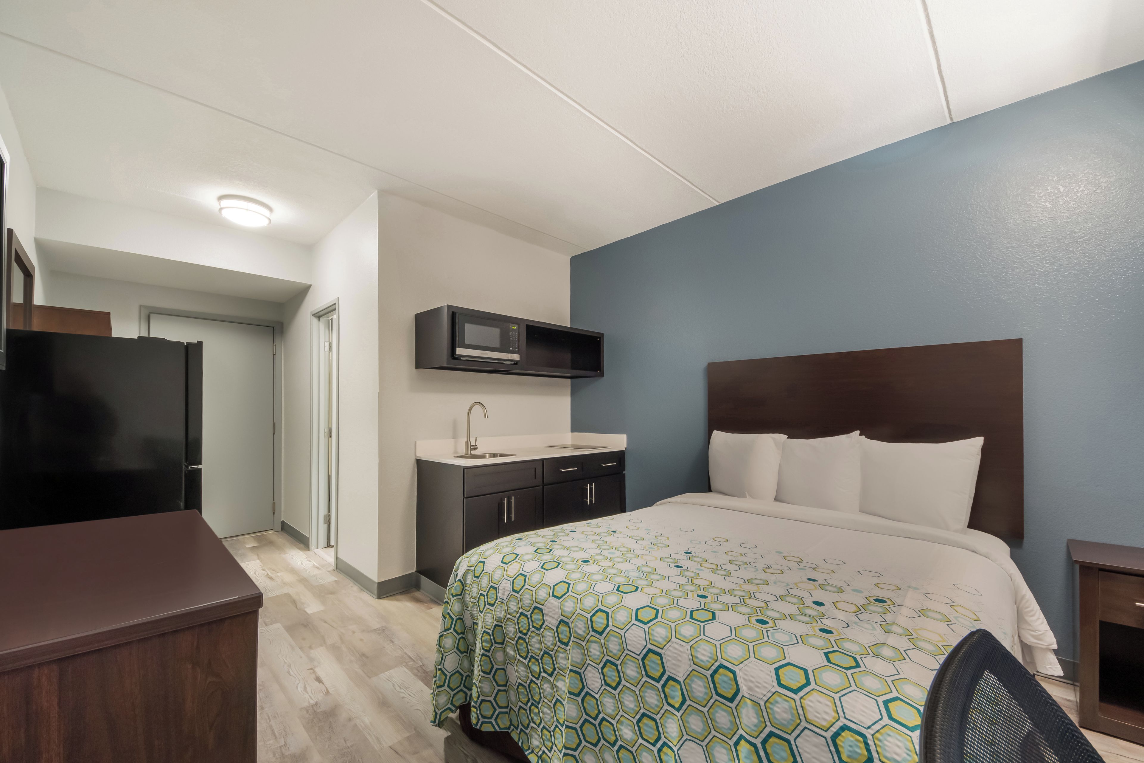 Ein Hotelzimmer mit einem Bett, einem Schreibtisch, einer Mikrowelle und einer kleinen Küchenzeile.