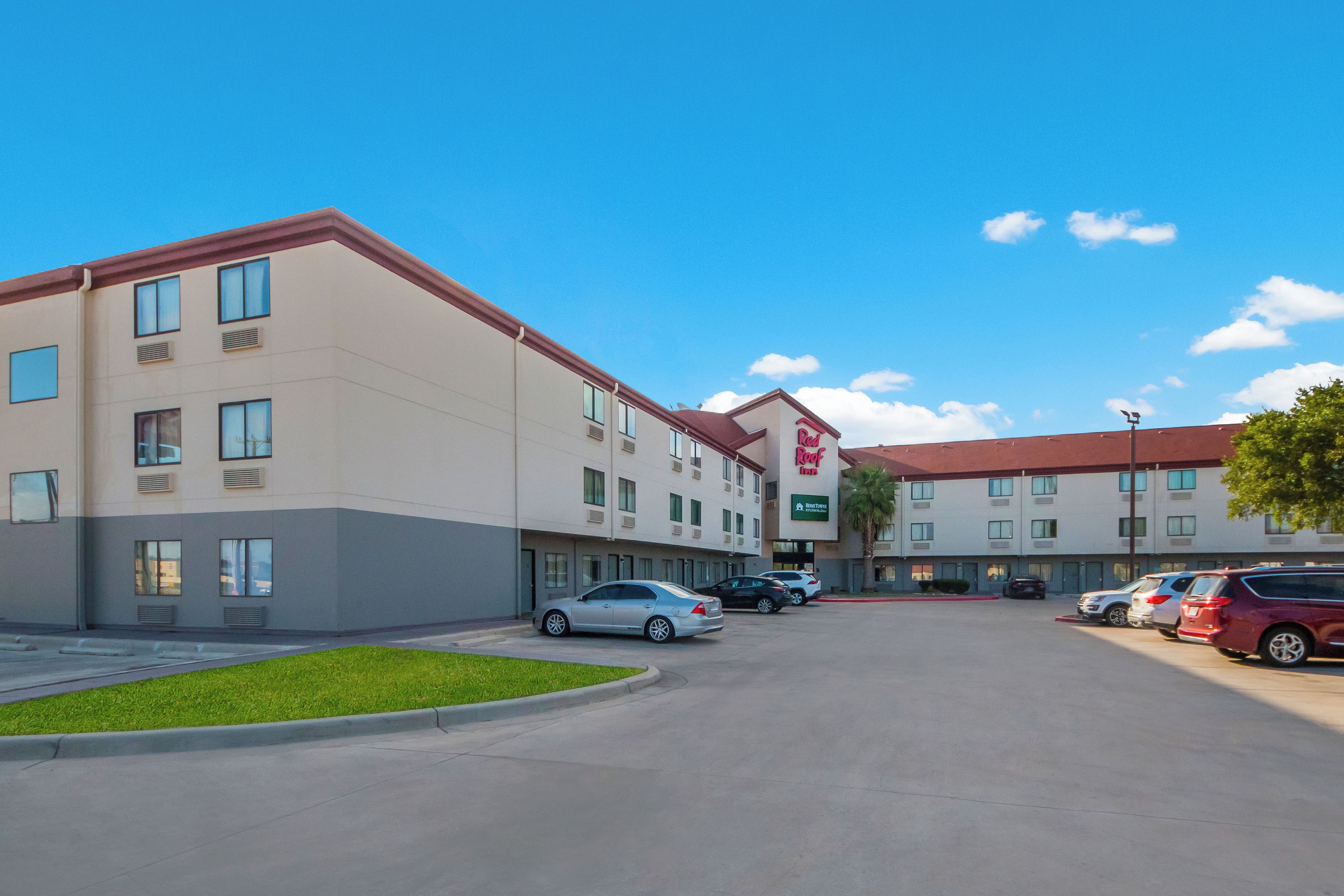 Ein Hotel mit Parkplatz, mehreren Autos und blauem Himmel.