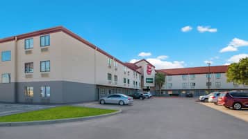 Een hotel met een parkeerplaats, meerdere auto's en een heldere lucht.