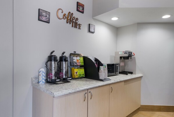 Una estación de café con una máquina de café, espumador de leche y molinillo.
