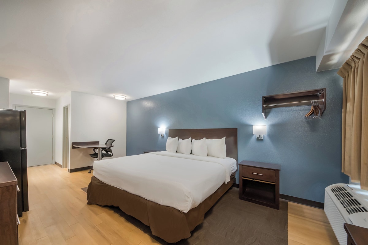 Habitación de hotel con una cama grande, un escritorio, una silla, un armario y un calentador instalado en la pared.