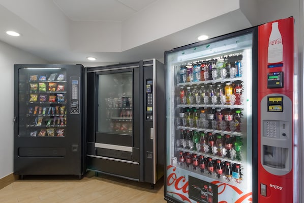 Trois distributeurs automatiques de boissons proposant une variété de choix.