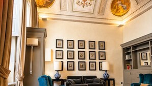 Ein Wohnzimmer mit einer Couch, Sesseln, einem Couchtisch, gerahmten Bildern an der Wand und einem Chandelier.