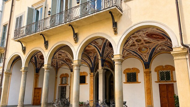 Ein Gebäude mit einem Balkon, gewölbten Säulen und einem Fliesenboden.