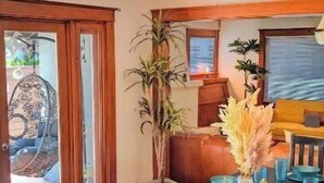 A dining area with a dark wooden table set for four, blue glassware, and a ceiling fan. - Craftsman 4 Bed/2 Ba. Home Sleeps 10, AC & Parking (Long Beach)