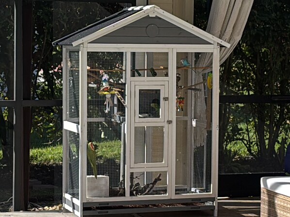 A white birdcage with multiple compartments, a door, and a roof.