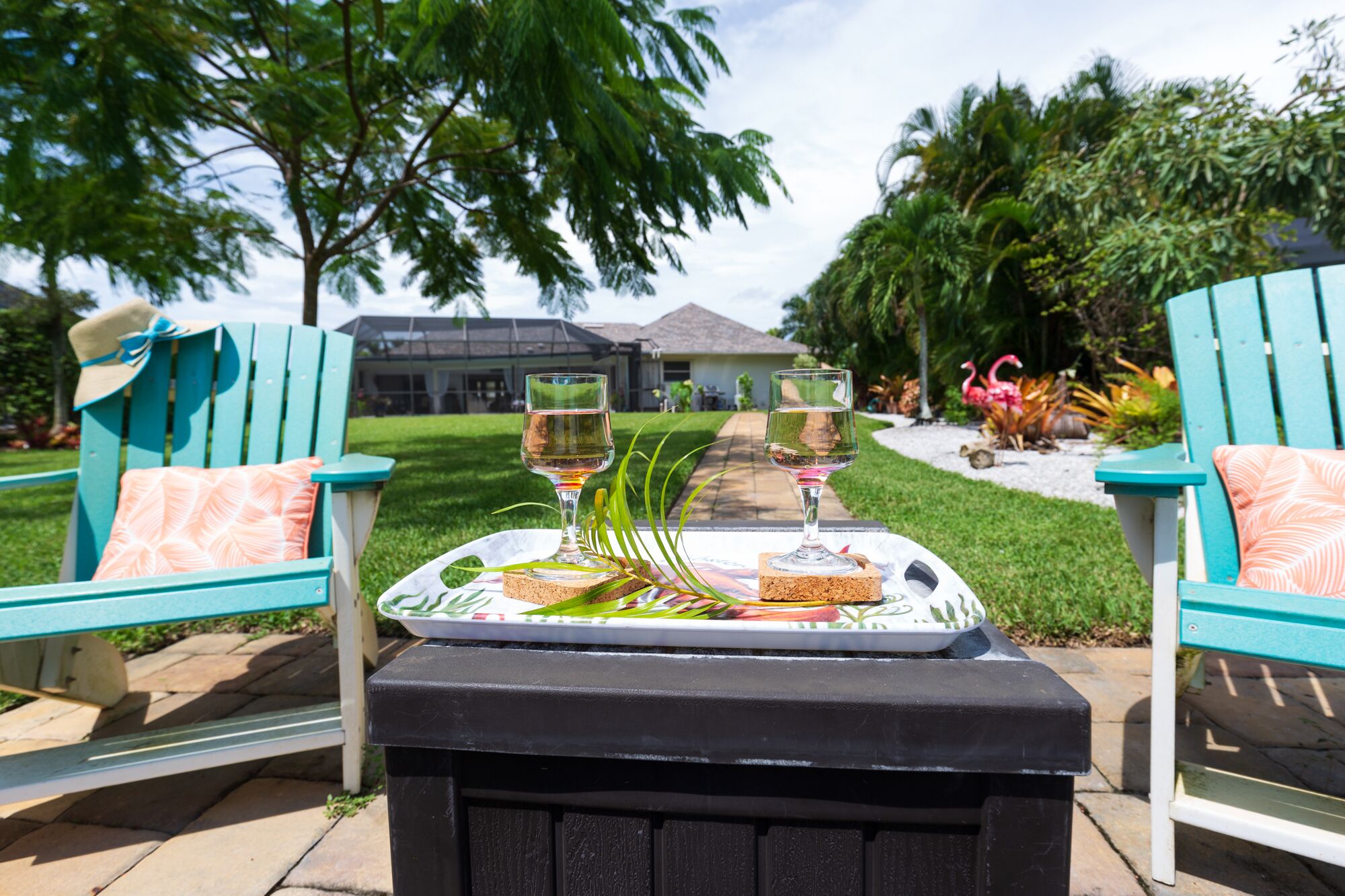 A patio with two turquoise chairs, a table with a cork coaster, and two wine glasses.