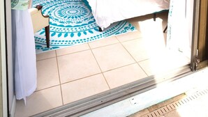 Quarto com cama, cortinas, ventoinha no teto e tapete estampado.
