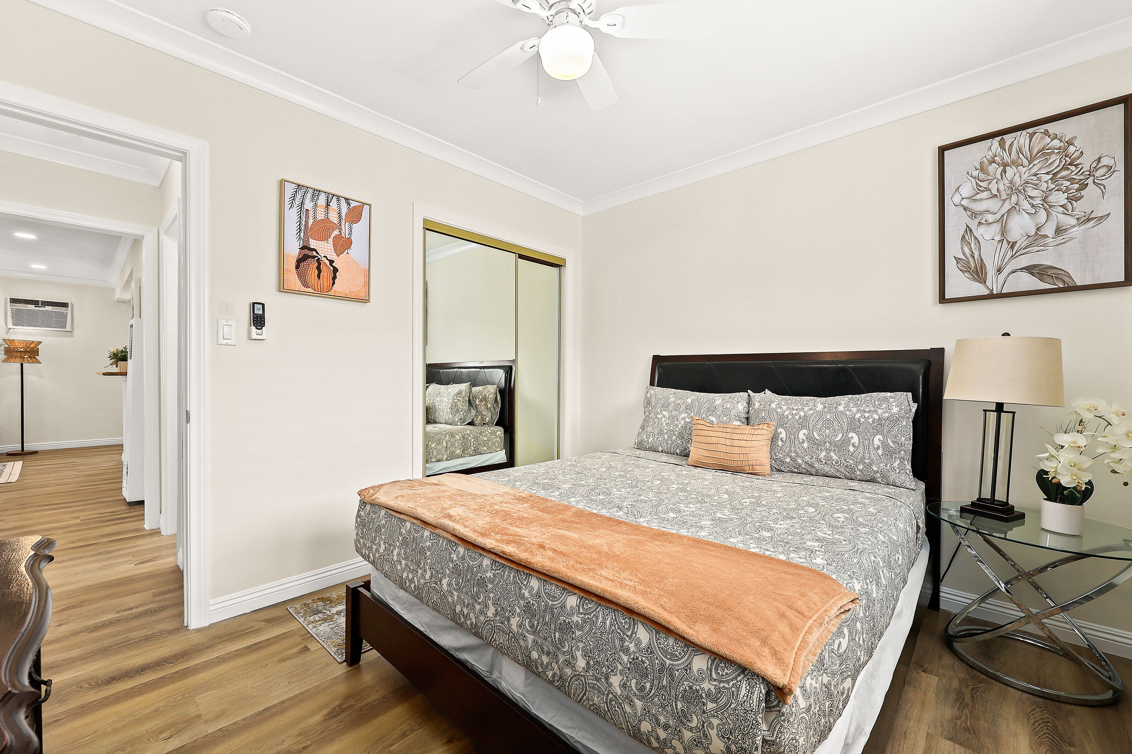 A bedroom with a bed, bedside table, lamp, and a mirror.