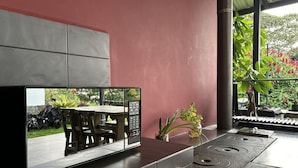 Una cocina con estufa integrada, un comedor con mesa y sillas, y un amplio ventanal con vistas a zonas verdes.