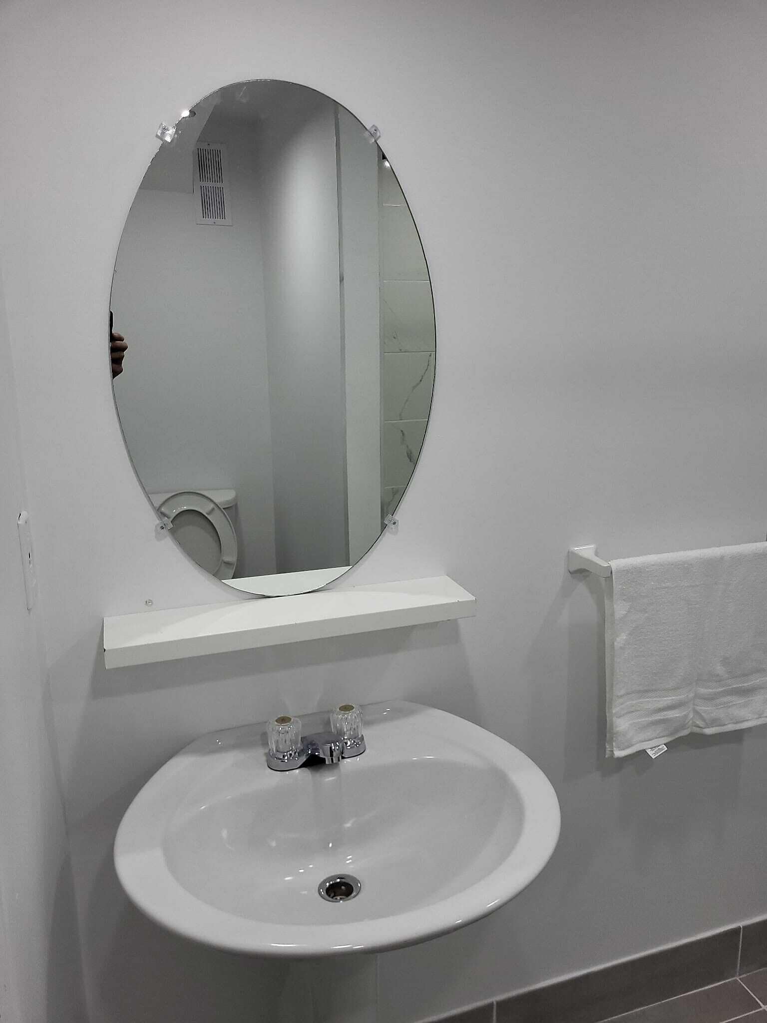 A bathroom with a round mirror, a white sink, and a towel rack.