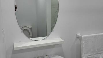A bathroom with a round mirror, a white sink, and a towel rack.