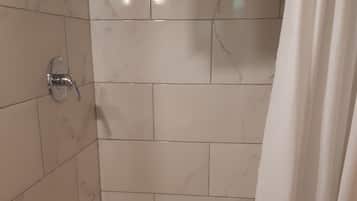 A shower area with hexagonal tiles, a shower curtain, and a tiled wall.
