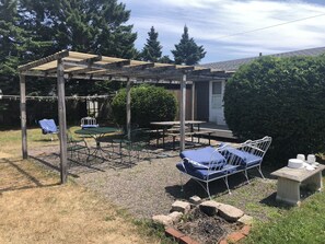 Relax in the serene patio area surrounded by lush greenery and a pergola, featuring a table, chairs, bench, and swing.