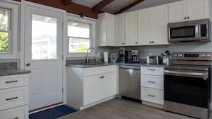 Eine Küche mit weißen Schränken, einer Edelstahl-Mikrowelle, einem Geschirrspüler und einem Backofen.