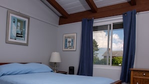 Ein Schlafzimmer mit einem Bett, einem Nachttisch, einer Lampe und einem Fenster mit Vorhängen.