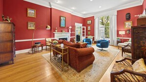 Un salon avec un mur rouge, des meubles en bois et une cheminée.