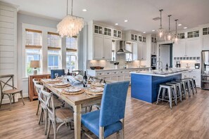 A spacious kitchen with white cabinetry, a central island, and bar stools.