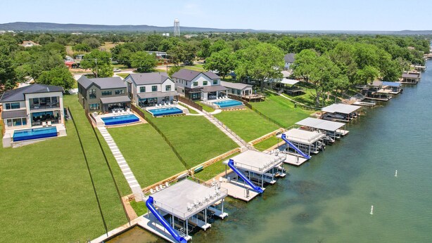 A residential area with modern houses, a swimming pool, and a dock with boats. - Waterhouse at Lake LBJ Residence III 6 King Beds, Pool/Spa, Boat/PWC Lift, Slide (Kingsland)