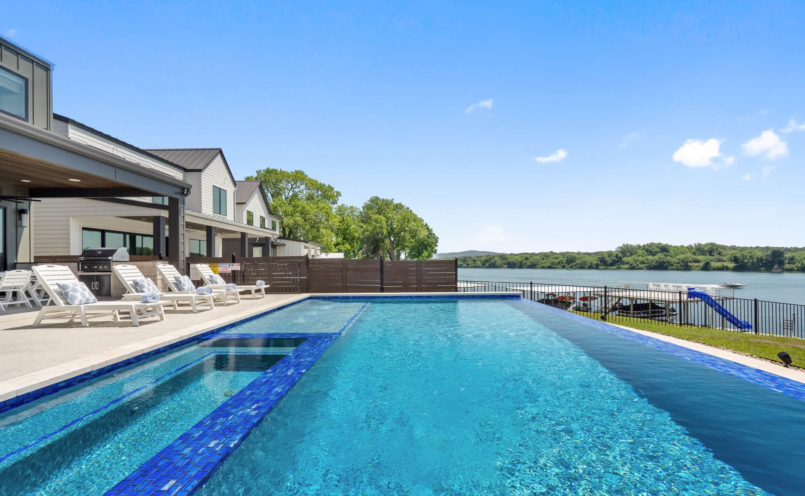 A swimming pool with lounge chairs and a view of a lake.