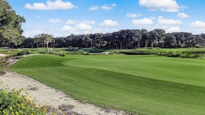 Un campo de golf con cielo despejado, árboles y un estanque.