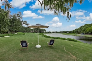 A golf course with two chairs and an umbrella, surrounded by trees and a lake. - NEW- Discount! POOL - near beach and golf course! (Fernandina Beach)