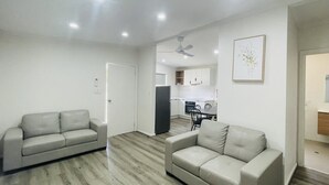 Una sala moderna con dos sofás, un comedor y una cocina al fondo.
