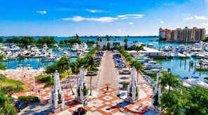 A marina with boats docked, a central walkway, and a building in the background.