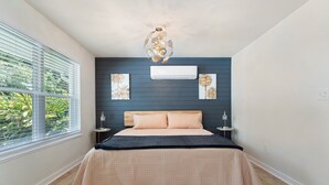 Un dormitorio con cama, lámpara en el techo y ventana con persianas.