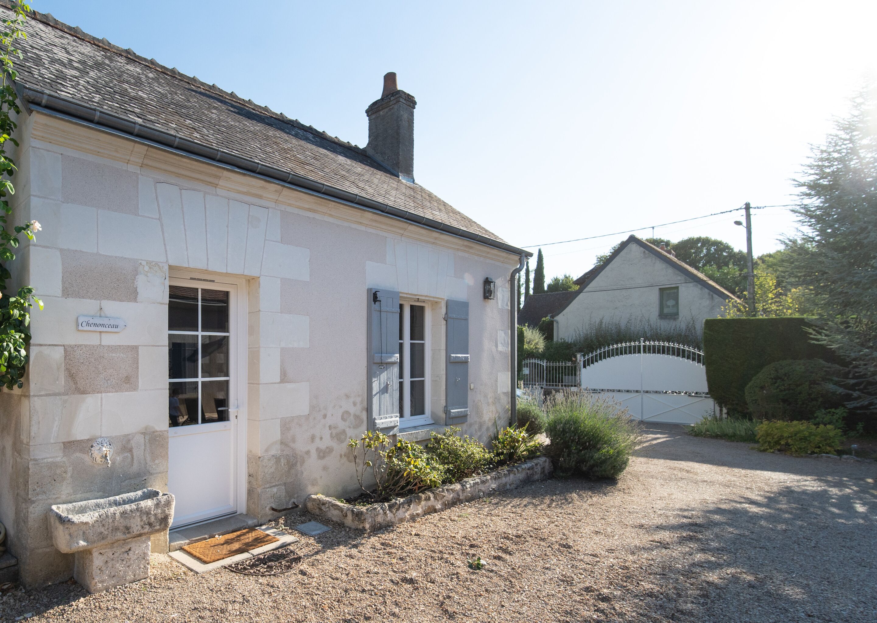A stone building with a white door, a small porch, and a gravel driveway.