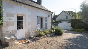 A stone building with a white door, a small porch, and a gravel driveway. - La Bulle d'Or-House-Deluxe-Whirlpool bath-Garden view (Francueil)