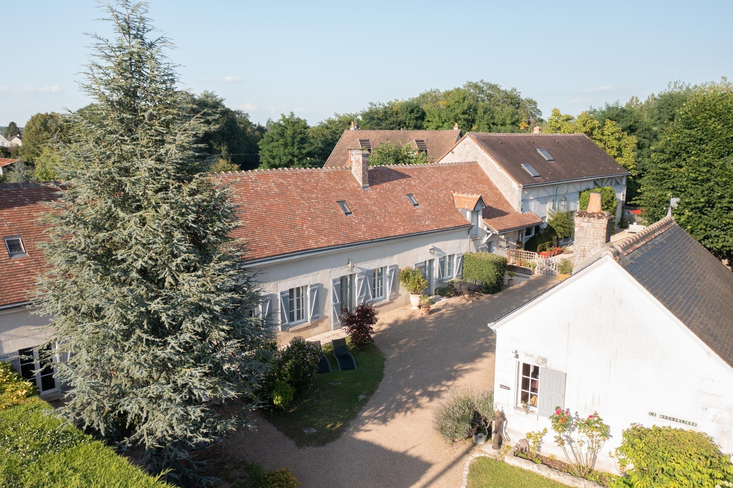 Un bâtiment de style européen traditionnel, doté d’un toit en tuiles, entouré d’une végétation luxuriante et d’un jardin bien entretenu.