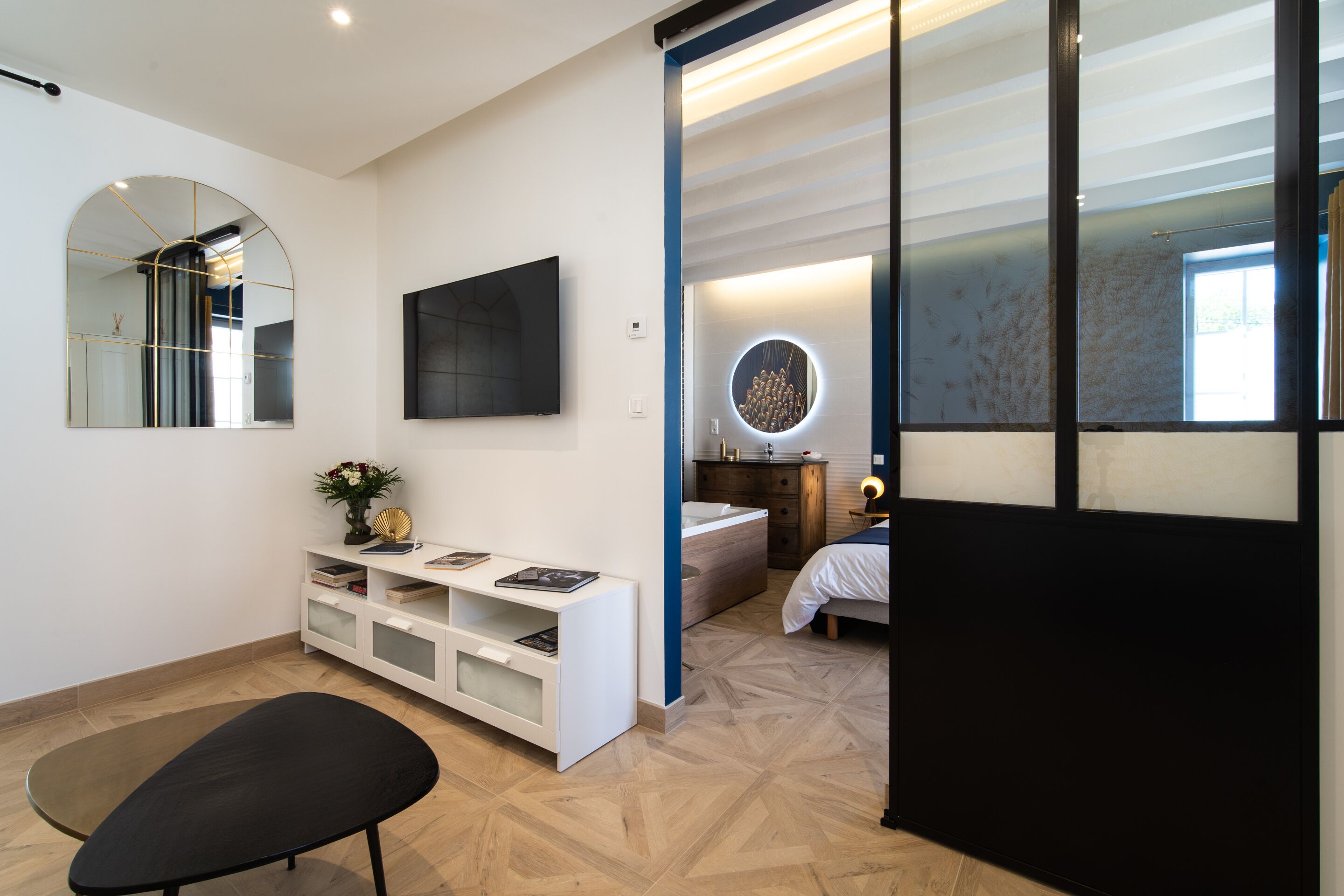 A modern bedroom with a bed, bedside table, and a large mirror.