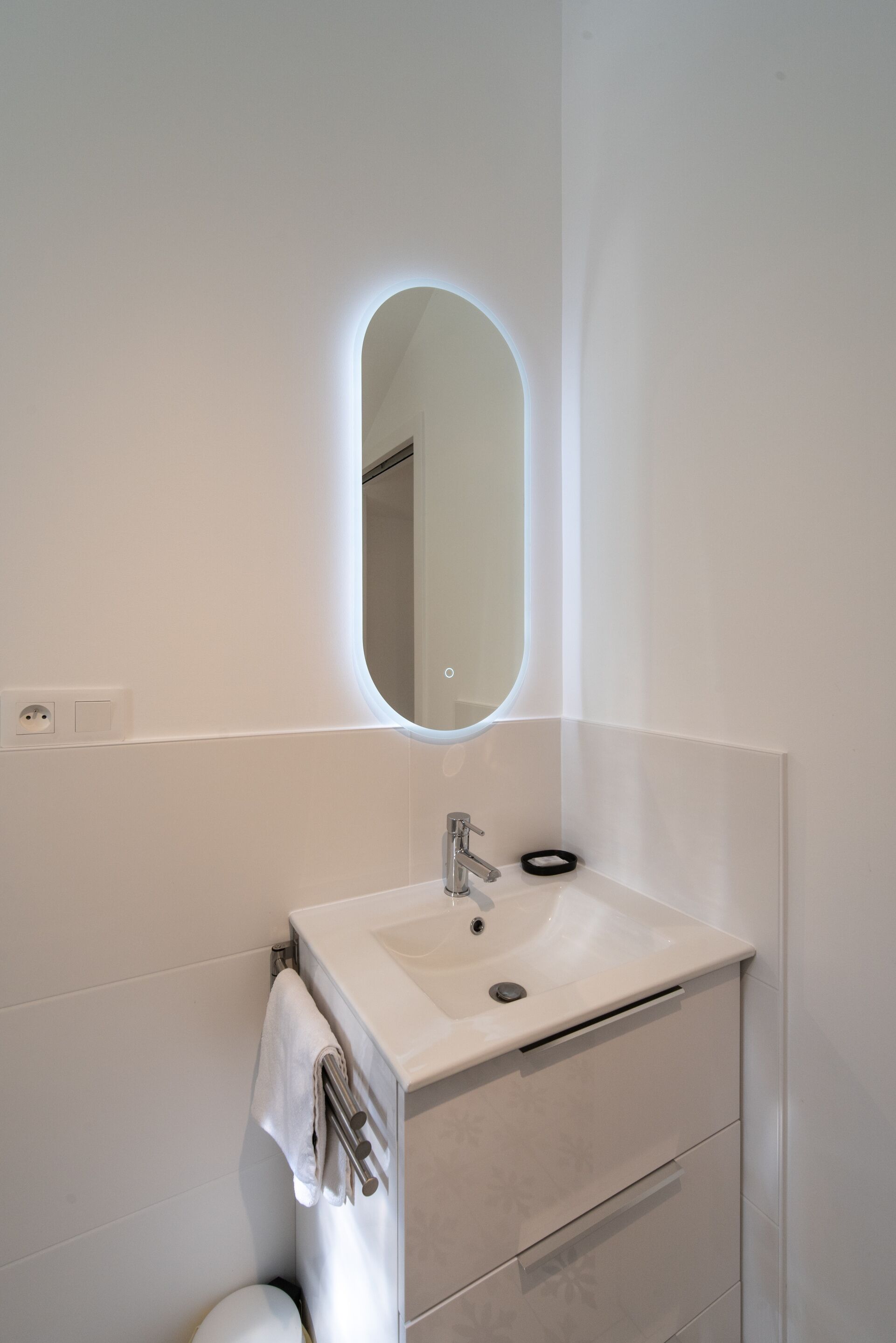 Une salle de bain avec un lavabo blanc, un miroir et un porte-serviettes.