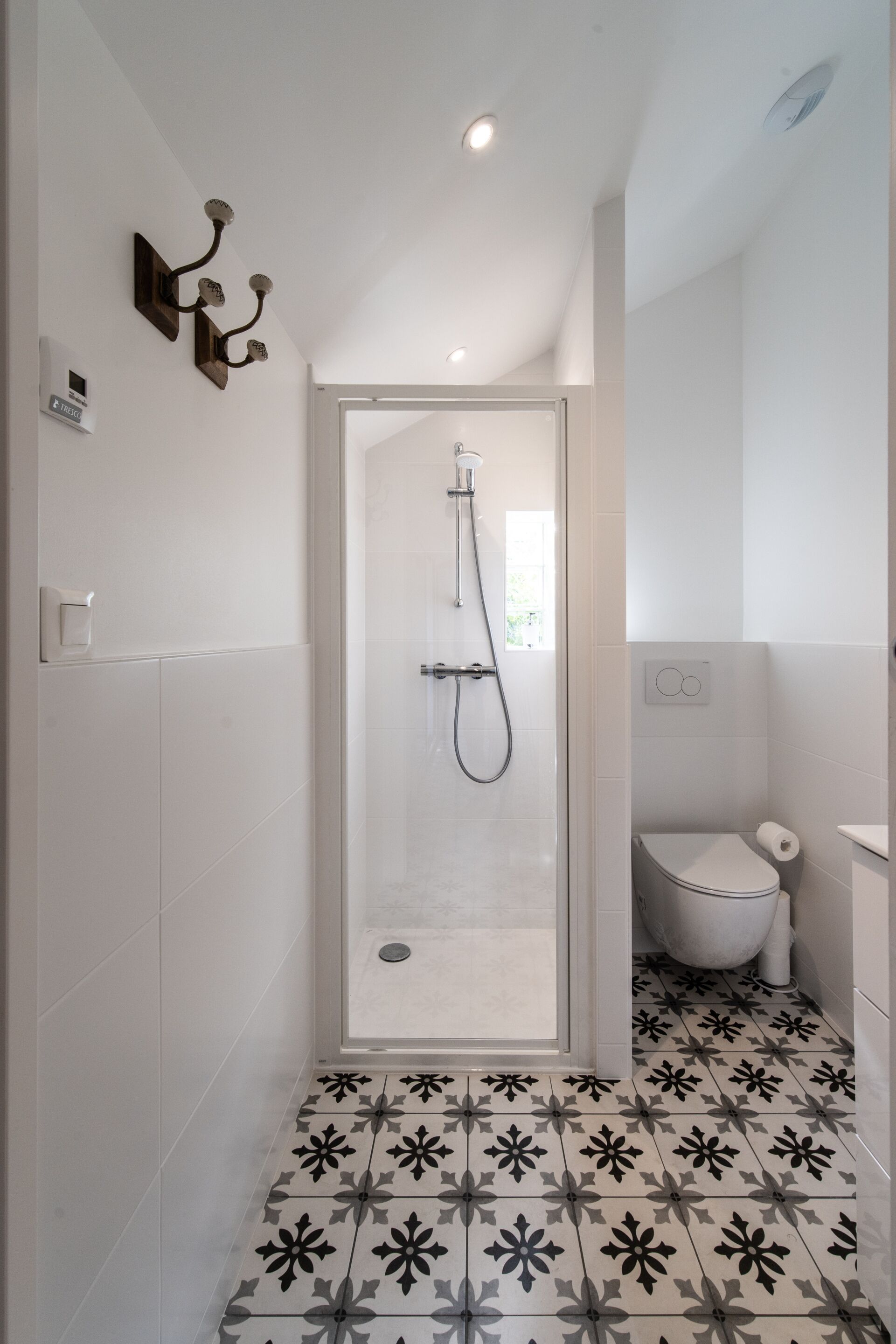 Ein modernes Badezimmer mit Dusche, Toilette und Fliesenboden mit Muster.