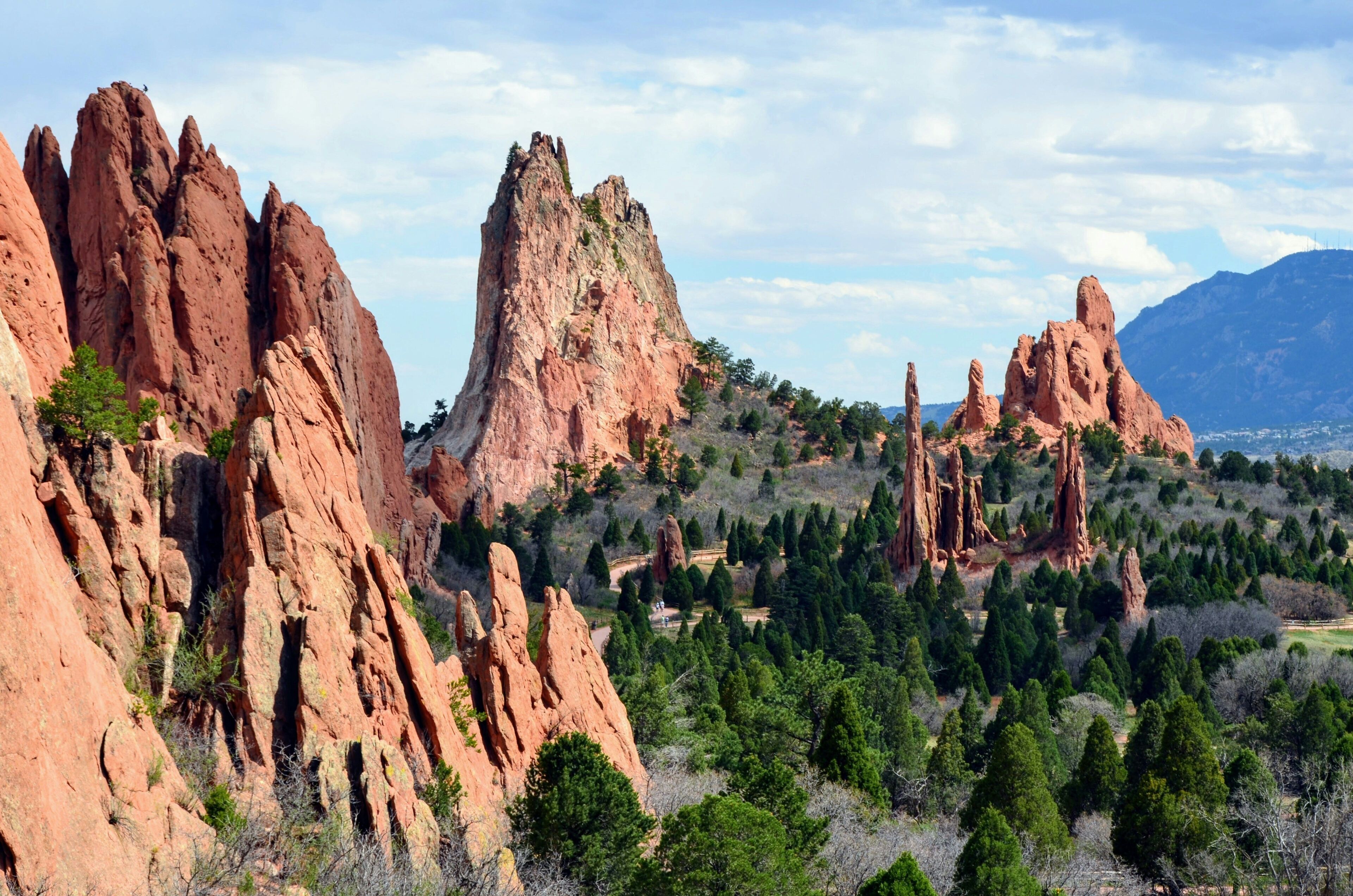 A mountainous landscape with prominent red rock formations and dense green forest.