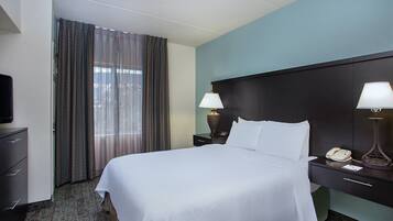 A hotel room with a bed, a TV, a desk with a lamp, and a telephone.