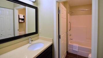 A bathroom with a sink, mirror, and shower.