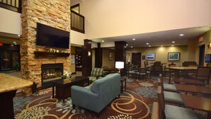 Recepció d'hotel amb una llar de pedra, seients confortables, un televisor de pantalla plana i una zona de dinar.