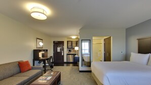 Une chambre d’hôtel comprenant un lit, un canapé, un bureau et une petite kitchenette.