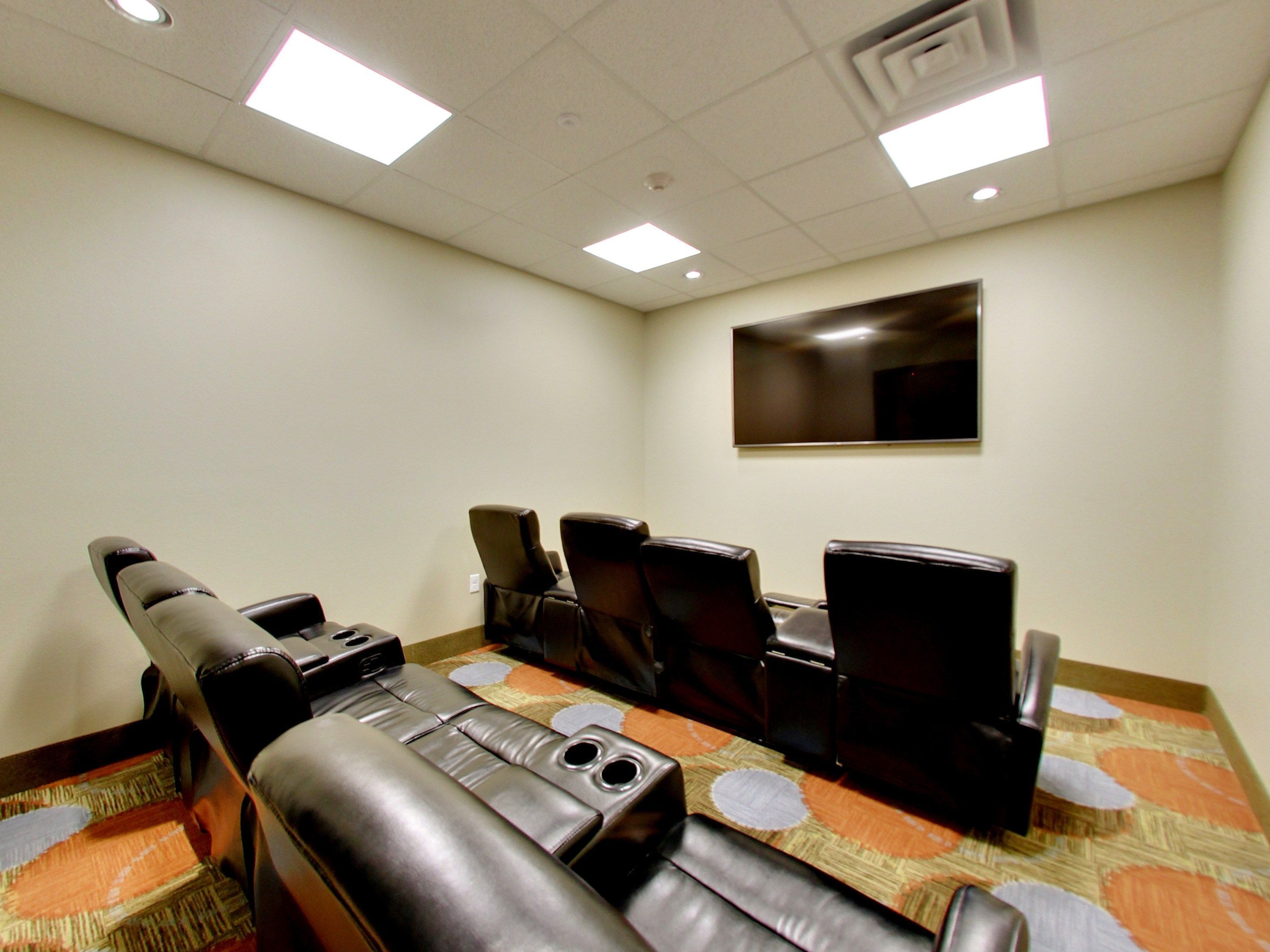 A conference room with leather chairs, a flat-screen TV, and a carpeted floor.