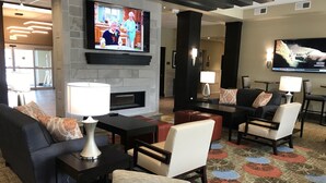 Un hall d’hôtel doté d’une cheminée, d’un coin salon et d’un téléviseur diffusant une émission de cuisine.