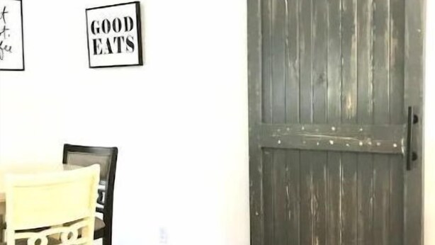 Un coin repas avec une table et des chaises en bois, une porte en bois foncé et deux panneaux encadrés accrochés au mur.