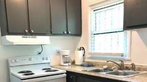 Une cuisine équipée d’une cuisinière, d’un évier, de meubles de rangement sombres et d’un tapis à motifs.