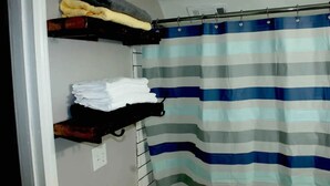 Ein Badezimmer mit einer gestreiften Duschvorhang, einem Handtuchhalter mit gefalteten Handtüchern und einer Ablage mit einem Handtuch.