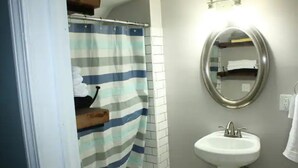 Ein Badezimmer mit gestreifter Duschvorhang, einem weißen Waschbecken und einem Spiegel.