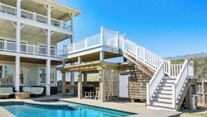 A two-story house with a swimming pool, a covered patio, and a staircase leading to a deck. - Happy Sol *9 bedroom*Oceanfront*Elevator*Pool (Nags Head)