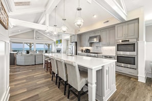 A spacious kitchen with a large island, modern appliances, and a view to the outside.