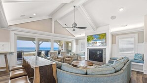 A spacious living area with a large sofa, a fireplace, and a view of the ocean. - Happy Sol *9 bedroom*Oceanfront*Elevator*Pool (Nags Head)